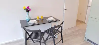 a small table with two chairs and a vase with flowers at Modern 2 BR Apartment near Town in Newmarket