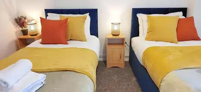 two beds with colorful pillows in a room at Modern 2 BR Apartment near Town in Newmarket