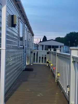 a porch of a house with a wooden deck at 8 Bed Sun Decked Caravan Unlimited High speed Wifi and fun at Seawick Holiday Park in Clacton-on-Sea