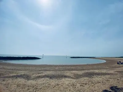 a beach with a group of people sitting on the sand at 8 Bed Sun Decked Caravan Unlimited High speed Wifi and fun at Seawick Holiday Park in Clacton-on-Sea