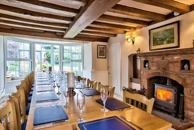 a dining room with a long table and a fireplace at Ashfield Place Farm by Group Retreats in Stowmarket