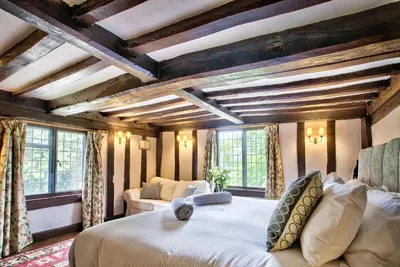 a bedroom with a large bed in a room with wooden ceilings at Ashfield Place Farm by Group Retreats in Stowmarket
