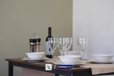 a table with wine glasses and bowls and a bottle of wine at Cozy House By AR Properties Short Lets & Serviced Accommodation Colchester in Colchester