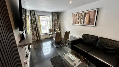 a living room with a leather couch and a table at 2 Bedroom Flat Ground Floor Town Centre Colchester in Colchester