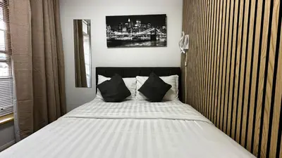 a bedroom with a white bed with black pillows at 2 Bedroom Flat Ground Floor Town Centre Colchester in Colchester