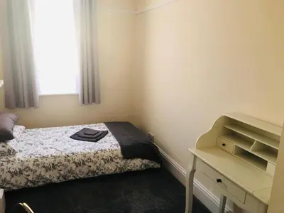 a small bedroom with a bed and a desk at AC Lounge 119a in Rochford