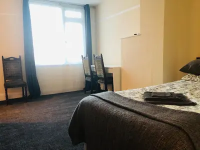 a bedroom with a bed and chairs and a window at AC Lounge 119a in Rochford