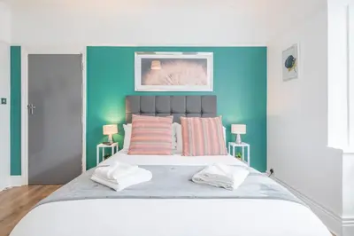 a bedroom with a large bed with a blue wall at The Modern Cambridge Studio 1 in Chesterton