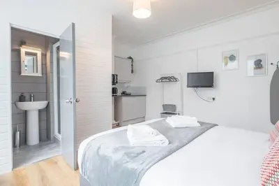 a white bedroom with a bed and a sink at The Modern Cambridge Studio 1 in Chesterton
