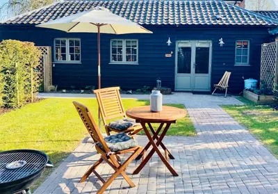 a table and two chairs and an umbrella in a yard at The BeeKeepers - Homely Luxurious Self Catering in Diss