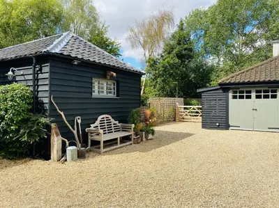 a black house with a bench next to a garage at The BeeKeepers - Homely Luxurious Self Catering in Diss