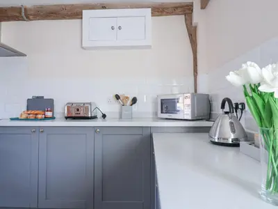 a kitchen with gray cabinets and a counter top at South Grange House - Sleep 16 in Saxmundham