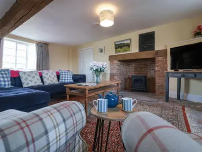 a living room with blue couches and a fireplace at South Grange House - Sleep 16 in Saxmundham