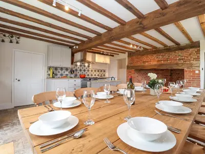 a dining room with a wooden table with wine glasses at South Grange House - Sleep 16 in Saxmundham