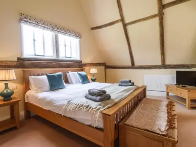 a bedroom with a large bed and a tv at South Grange House - Sleep 16 in Saxmundham