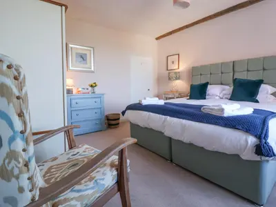 a bedroom with a large bed and a chair at South Grange House - Sleep 16 in Saxmundham