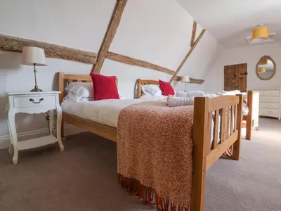 a bedroom with a large bed with red pillows at South Grange House - Sleep 16 in Saxmundham