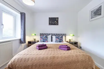 a bedroom with a large bed with purple pillows at Stylish 3 bedroom House In Grt Gregorie Basildon & Essex - Free Wifi, Parking, Dedicated Office & Private Garden in Basildon