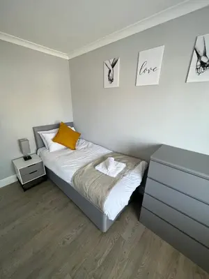 a small bedroom with a bed and a dresser at 3 bed luxury open plan living in Rayleigh