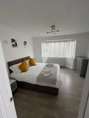 a bedroom with a large bed with yellow pillows at 3 bed luxury open plan living in Rayleigh
