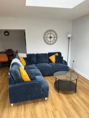a living room with a blue couch and a table at 3 bed luxury open plan living in Rayleigh