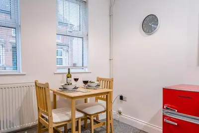a dining room table with two chairs and a red refrigerator at 1 Abbey Mews, Leiston in Leiston