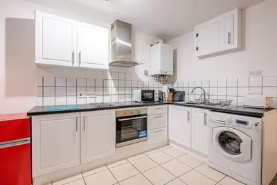 a kitchen with white cabinets and a washer and dryer at 1 Abbey Mews, Leiston in Leiston