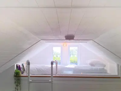 a bed in a white room with a window at The Little Barn in Hoxne