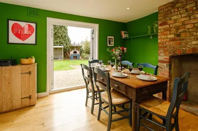a dining room with a table and green walls at Frogmore Cottage in Leiston