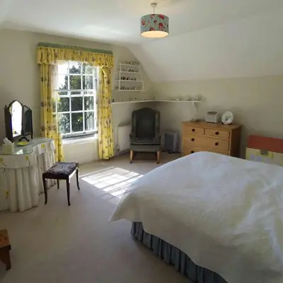 a bedroom with a bed and a chair and a window at The Old Rectory, Kettlebaston in Lavenham