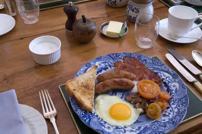 a blue and white plate of food with eggs sausage and toast at The Old Rectory, Kettlebaston in Lavenham