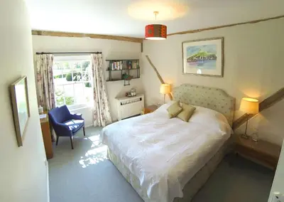 a bedroom with a bed and a chair and a window at The Old Rectory, Kettlebaston in Lavenham