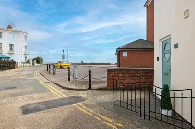 a yellow car driving down a street next to a building at Beach Front House in Walton-on-the-Naze