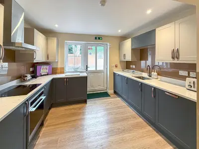 a large kitchen with blue cabinets and wooden floors at Breckland Thatched Cottage in Hockwold cum Wilton