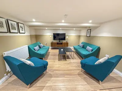 a living room with blue chairs and a flat screen tv at Breckland Thatched Cottage in Hockwold cum Wilton