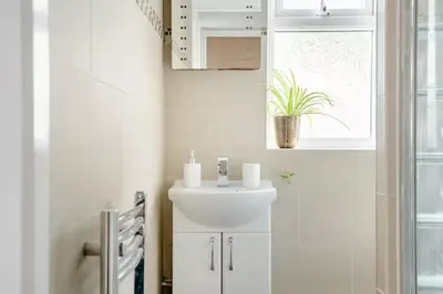a white bathroom with a sink and a window at Fourwinds in Maldon