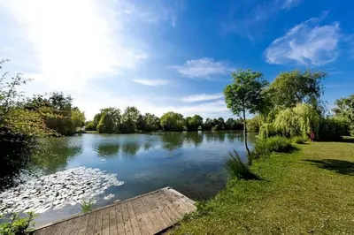 a view of a river with a wooden dock at Platinum lodge on Carlton Meres holiday Park in Rendham