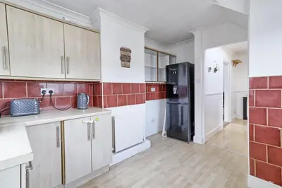 a kitchen with white cabinets and a black refrigerator at Elegant 3 Bedroom House in Basildon - Essex Free Parking & Superfast Wifi, upto 6 Guests in Basildon