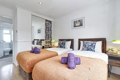 two beds in a hotel room with purple towels at Elegant 3 Bedroom House in Basildon - Essex Free Parking & Superfast Wifi, upto 6 Guests in Basildon