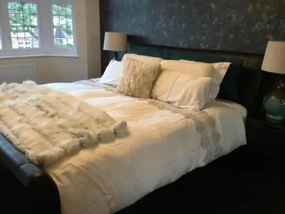 a large bed with white sheets and pillows at Fabulous 4 Bed Home with Gym in Basildon