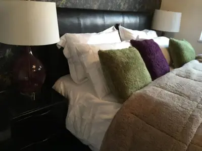 a bed with pillows on it next to two lamps at Fabulous 4 Bed Home with Gym in Basildon