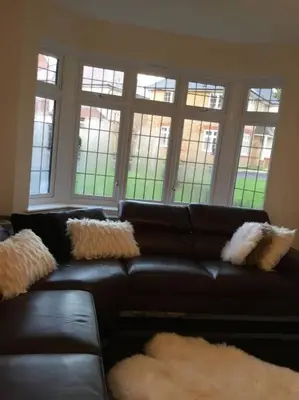 a black leather couch in a living room with windows at Fabulous 4 Bed Home with Gym in Basildon