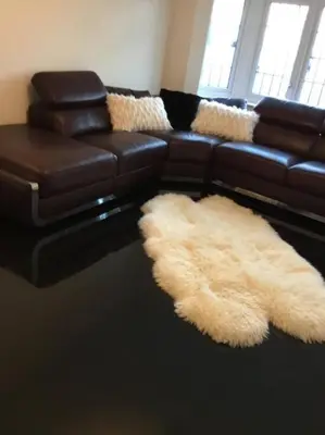 a living room with a leather couch and furry rugs at Fabulous 4 Bed Home with Gym in Basildon