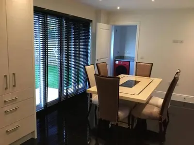 a dining room with a table and chairs and a window at Fabulous 4 Bed Home with Gym in Basildon