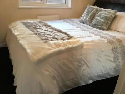 a white bed with a blanket on top of it at Fabulous 4 Bed Home with Gym in Basildon