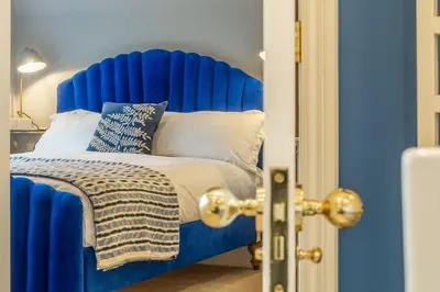 a blue bed with a blue headboard in a room at The Farmhouse, Nether Hall Estate in Pakenham