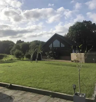 a house with a grassy yard in front of it at Willow Barn luxury countryside accommodation in Bury St Edmunds in Bury Saint Edmunds