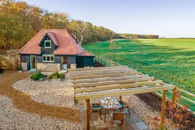 a small house with a red roof in a yard at Bumblebee Cottage in Barnham