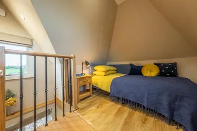 a bedroom with two beds and a window at Bumblebee Cottage in Barnham