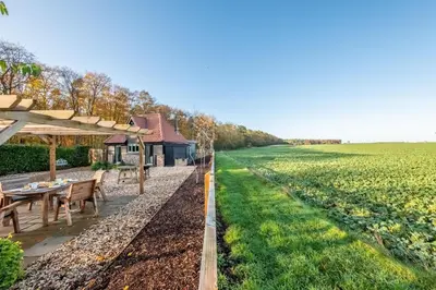 a farmhouse with a table and a field of crops at Bumblebee Cottage in Barnham